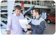 Deux professionnels en discussion devant un véhicule, soulignant la consultation personnalisée pour les services gratuits d'enlèvement d'épave